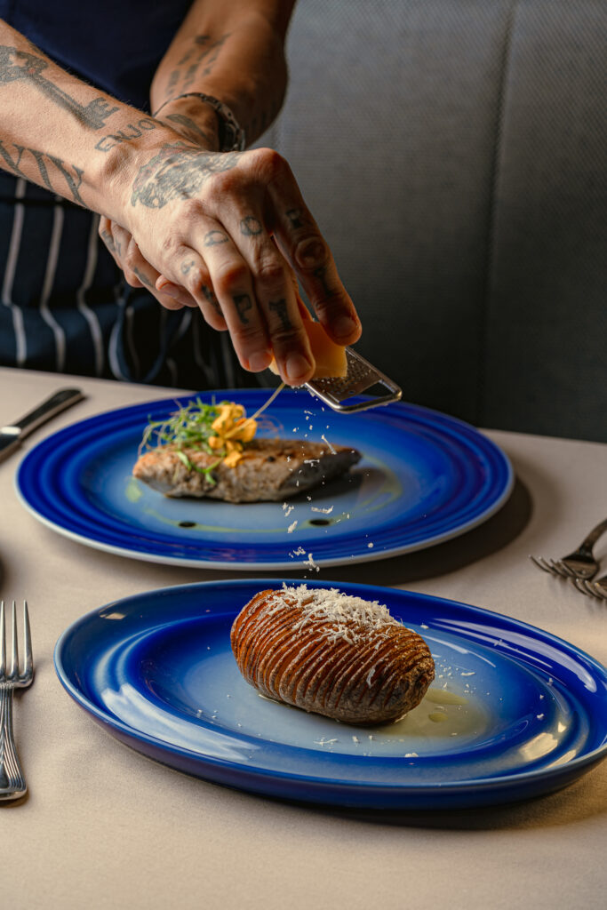 Chef grating cheese on hasselback potato